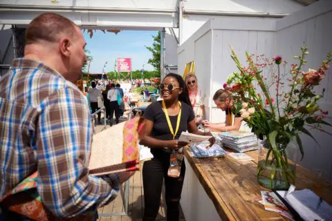 Gasten in gesprek met mbo-student Evenementenorganisatie op een festival waar deze student werkt