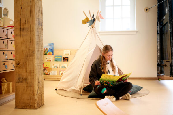 Student pedagogische medewerker kinderopvang zit op de grond in een speelgoedtentje